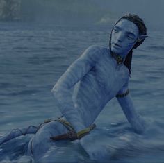 a man with blue paint on his body sitting in the water