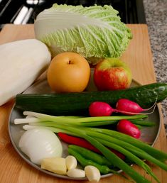 vegetables and fruits are on a plate next to an eggplant, carrots, onion, cabbage, and lettuce