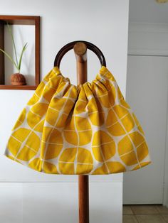 a yellow and white bag hanging on a wooden pole in front of a wall with a mirror