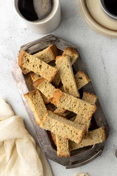 slices of bread on a tray next to two cups of coffee