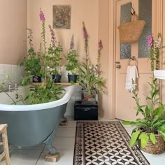 a bath tub sitting next to a white sink in a bathroom filled with plants and potted plants