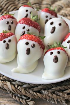 chocolate covered strawberries with white frosting in the shape of ghost faces on a plate