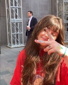 a woman making the peace sign with her hand while standing in front of a building