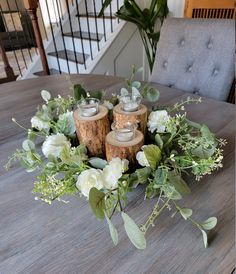 the table is set with candles, flowers and greenery on top of wood logs