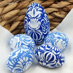 blue and white painted eggs sitting in front of a basket