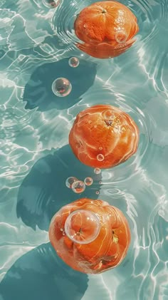 three oranges floating in the water with bubbles