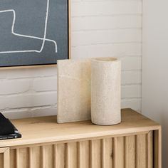 two concrete vases sitting on top of a wooden cabinet next to a chalkboard