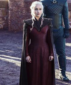 the game of thrones character is standing next to a man in a red dress