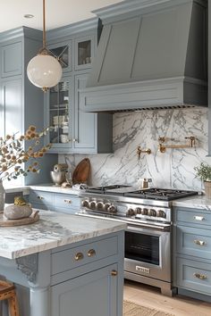 a kitchen with blue cabinets and marble counter tops, an island in front of the stove