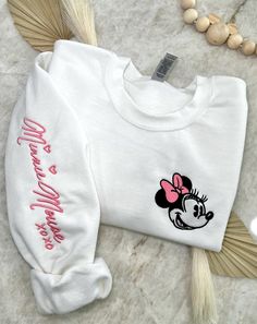 Cozy up in a bit of magic with our enchanting, Magical Autograph crewneck sweater. This sweater has a soft blended interior and features an embroidered face of the beloved Mrs. Mouse on the left side of the chest and her autograph alongside the right sleeve. It could not get any cuter than this! ✦Sweater design features two embroidered locations. ✦Choose your preferred colored crew! ✦Interested in a different character? Head over to our "All Crewnecks" tab or type 'Magical Autograph Crewneck' in the search bar to see the other characters! ✦Want to pair this sweater with our mouse ears? Browse our ear selection to find your favorite match! Disney Birthday Sweatshirt, Embroidered Crew Sweater For Winter, White Embroidered Sweatshirt For Winter, Cute Embroidered Long Sleeve Sweatshirt, Cute Long Sleeve Embroidered Sweatshirt, Cute Embroidered Sweatshirt Gift, Cute Long Sleeve Embroidered Sweater, Cozy White Embroidered Sweatshirt, Cute Custom Embroidery Sweatshirt For Winter