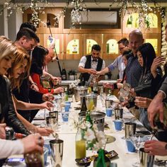 a group of people standing around a long table with glasses on it and plates in front of them