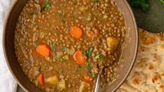 a bowl filled with lentula and carrots next to pita bread