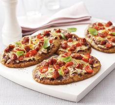 four small pizzas on a cutting board next to a glass of milk and napkin