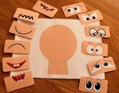 paper cut out with different faces and mouths on top of a wooden table in the shape of a human head