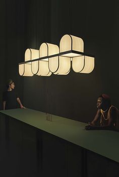 two people sitting at a table with lamps above them