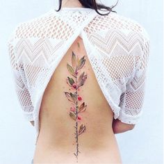 the back of a woman's body with tattoos on her ribs and flowers growing out of it