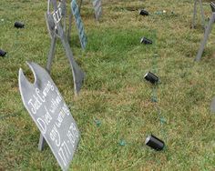 several tombstones in the grass with writing on them and broken glass bottles scattered around