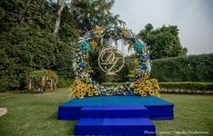 an outdoor ceremony setup with blue and yellow flowers in the center, surrounded by greenery