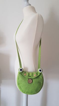 a white mannequin with a green purse on it's head and eyes