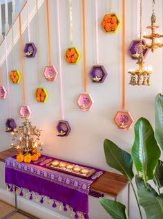 a purple table topped with donuts next to a wall covered in hexagonal decorations