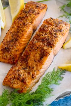 two salmon fillets on a plate with lemons and dill garnish