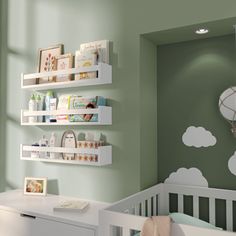 a baby's nursery room with green walls and white shelves on the wall next to a crib