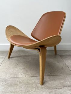 a wooden chair sitting on top of a tile floor next to a white wall with a brown leather seat