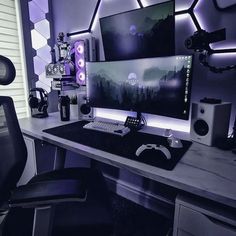 a desk with a computer and speakers on it in front of a purple light wall