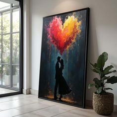 a couple kissing in front of a large painting on the wall next to a potted plant