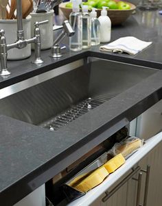 a kitchen sink that is open and has some food in the bottom drawer next to it