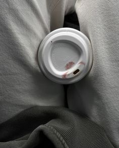 a white coffee cup sitting on top of a person's back with the lid down