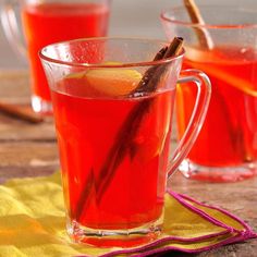 two glasses filled with red liquid and cinnamon sticks