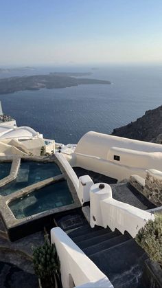 an outdoor jacuzzi overlooking the ocean on top of a hill with white buildings