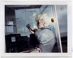 a woman is standing in front of a machine and talking on the phone with her hands behind her back