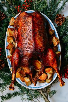 a whole turkey on a platter with potatoes and pine cones