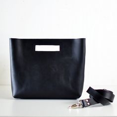 Say hello to the newest addition to the MB collection! She's a charming handbag with the option of including a removable crossbody strap! With clean lines & modern look, the unique cutout handle adds a bit of fun. Black LeatherBlack Leather Detachable Strap (optional) ... • Fast & FREE USPS Shipping• Open interior pocket• Hidden magnetic closures• Shiny nickel hardware• Measurements: 13" wide across top, 11” wide across bottom, 9.75" high, 3" deep• Detachable strap drop length: 24"• Handmade in Convertible Backpack Purse, Favorite Handbags, Convertible Backpack, Nickel Hardware, Honey Colour, Black Leather Handbags, Best Bags, Color Lines, Photo Colour