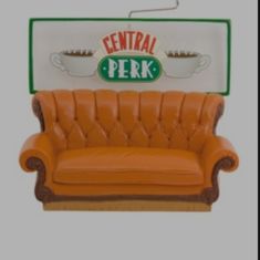 an orange leather couch sitting in front of a sign that says central perk on it