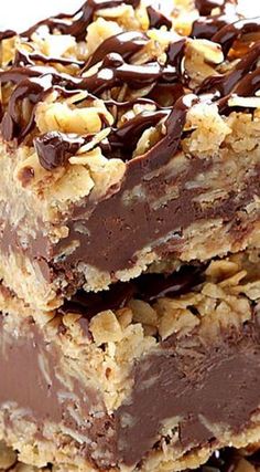 three pieces of chocolate peanut butter bars stacked on top of each other with chopped nuts