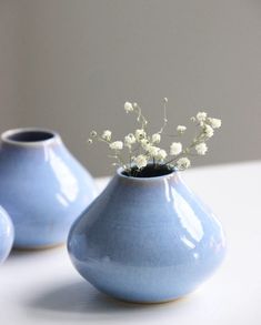 three blue vases with white flowers in them