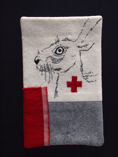 an embroidered patch with a red cross on it and a white dog in the center