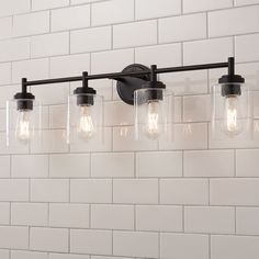 a bathroom light with five lights on it and white brick wall in the back ground