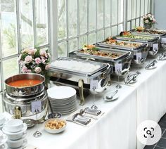 a buffet table filled with lots of food and silverware on top of white clothed tables