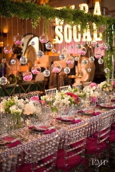 a long table is set with pink and white flowers, wine glasses, and candles