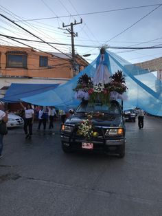 a car with flowers on the hood is parked in front of a blue tarp