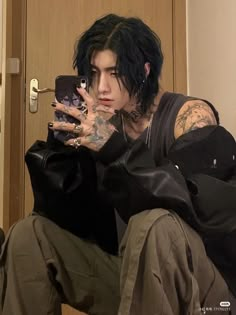 a man with black hair and piercings taking a selfie in front of a mirror