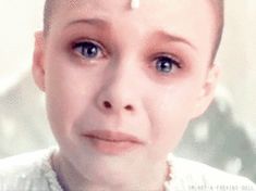 a woman with blue eyes and piercings on her head is looking at the camera