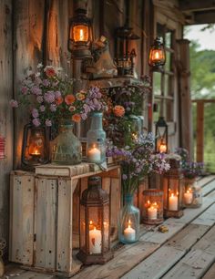 lanterns are lined up on the porch with flowers and candles in them, along with other decorations