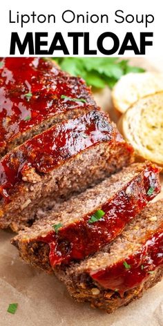 sliced meatloaf sitting on top of a piece of parchment paper next to bread