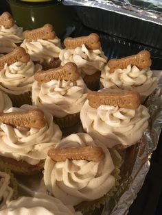 cupcakes with white frosting and dog bone decorations on top are sitting in tin foil