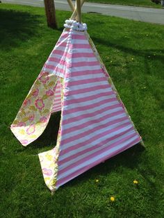 a pink and white striped teepee sitting in the grass